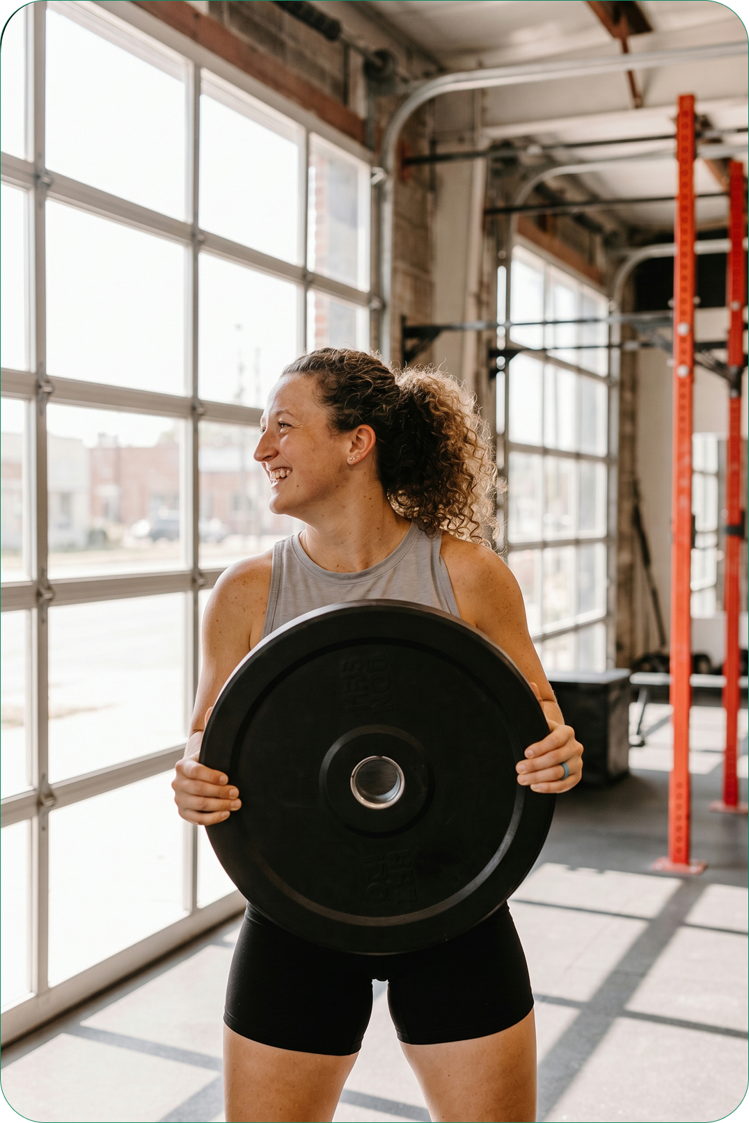Person holding a weight plate in a bright gym
